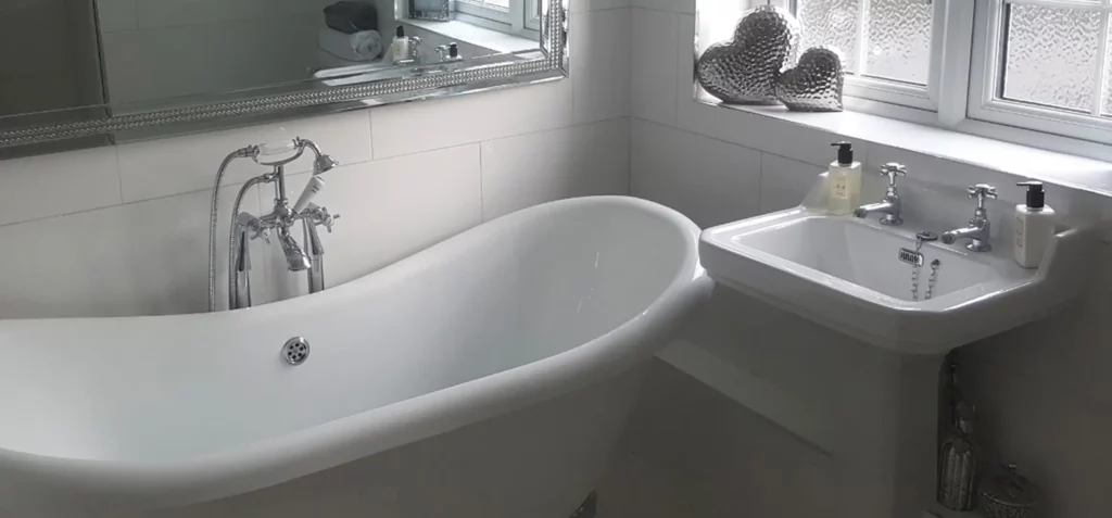 A free standing bath with chrome feet and large mirror installed in a bathroom refurbishment in Essex